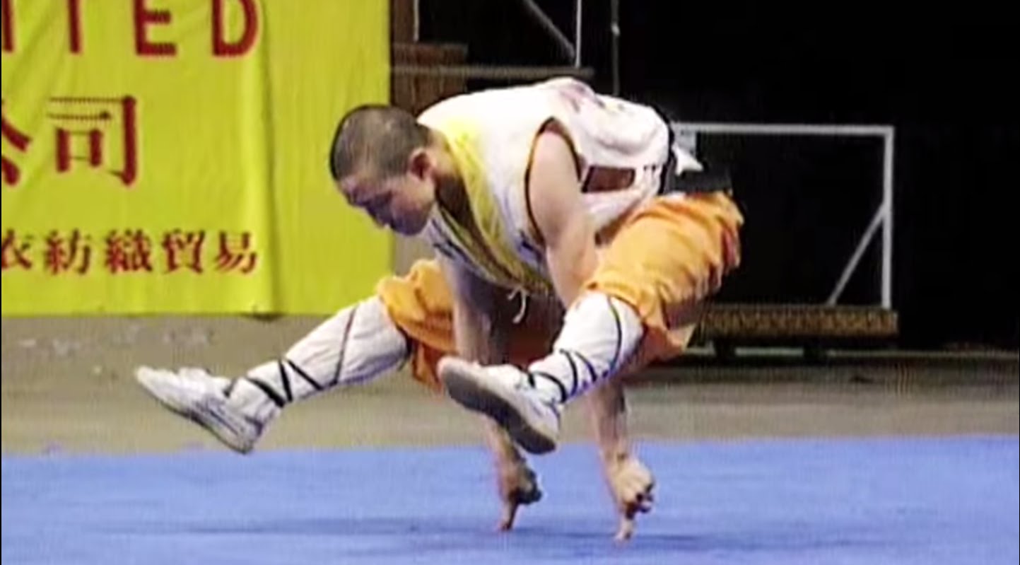 Shaolin monk balancing on pointer finger of each hand