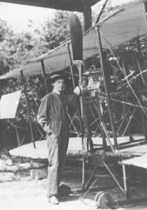 Woman in overalls standing in front of an early bi-plane